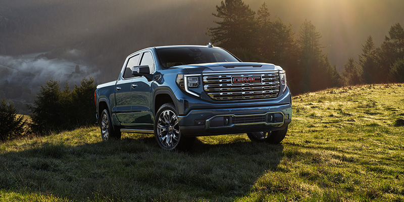 A black 2026 GMC Sierra 1500 is parked on a mountain meadow